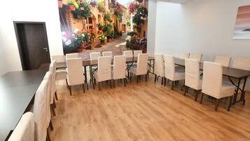 A conference room with a long table and chairs, a wooden floor, and a large window with a view of a street scene.