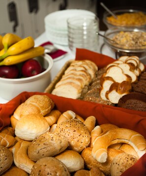 Variedad de panes y pasteles, incluyendo bagels y bollos, sobre una mesa.