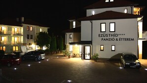 Ein Hotel mit einem Schild, auf dem 'EZÜSTHID PANZIO & ETEREM' steht, bei Nacht.
