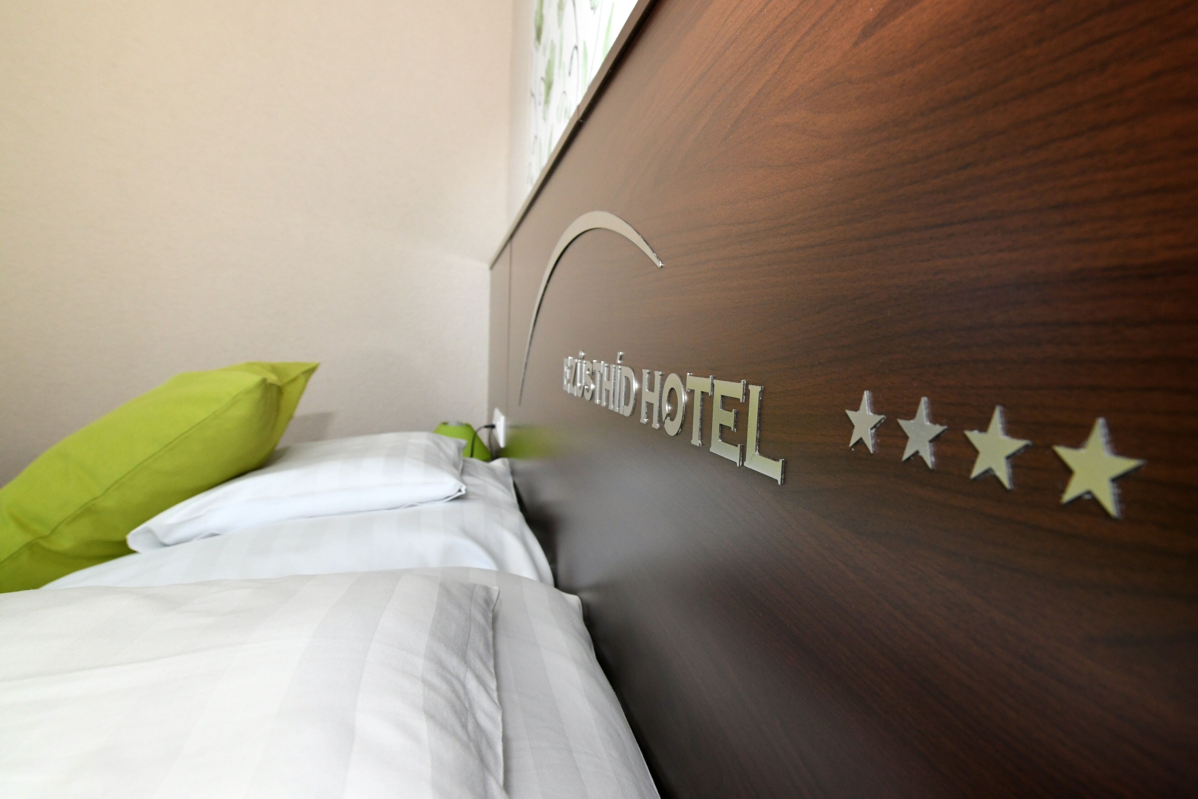 Una habitación de hotel con cama, almohadas y una pared que muestra el nombre del hotel y sus estrellas.