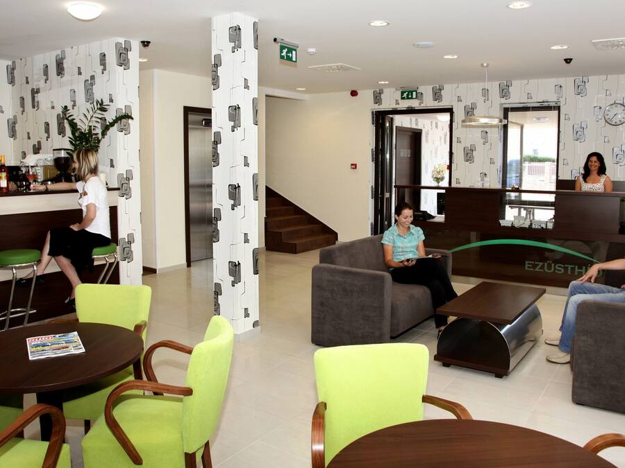 A modern hotel lobby with seating areas, a reception desk, and a bar.