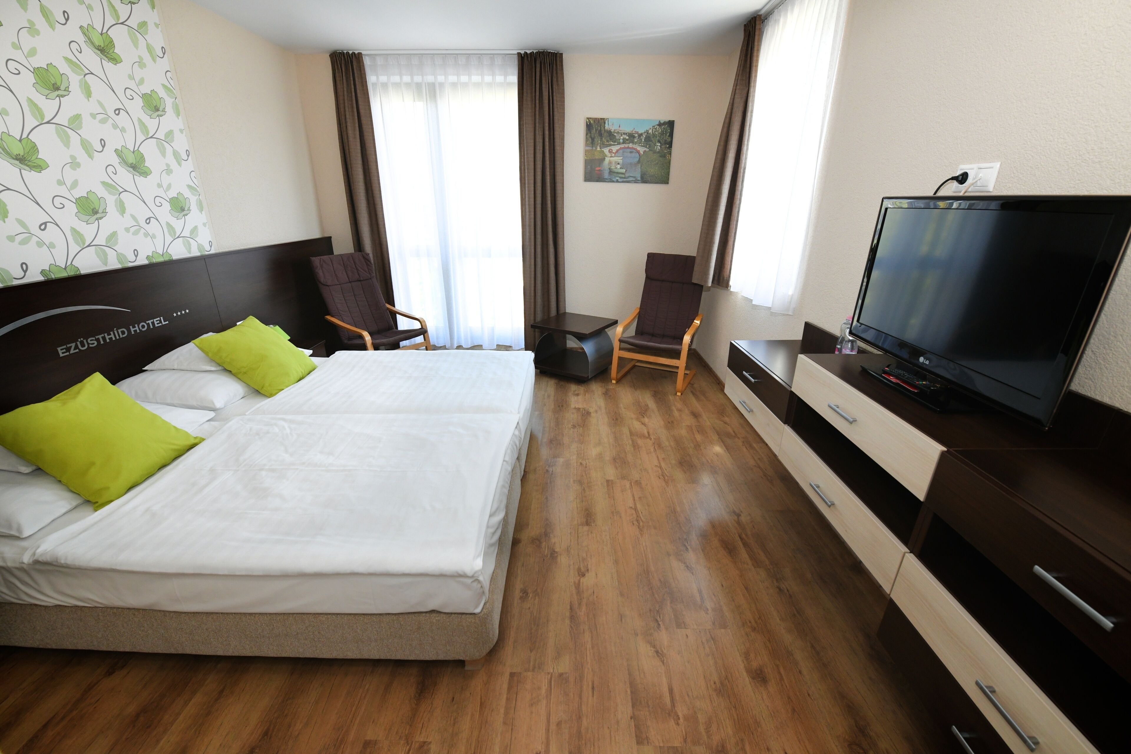 Hotellihuone, jossa on sänky, televisio, työpöytä ja tuoli.