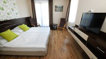 Hotellihuone, jossa on sänky, televisio, työpöytä ja tuoli.