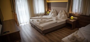 A hotel room with a bed, wooden floor, a nightstand with a lamp, and a TV on a wooden table. - Hotel Jade - Ezüsthíd Hotel (Veszprem)
