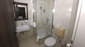 Un baño con ducha de vidrio, lavamanos, inodoro y espejo.