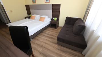 Et hotelværelse med seng, sofa, skrivebord og natbord.