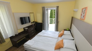 Habitación de hotel con cama doble, televisión, escritorio y balcón con vistas a zonas verdes.