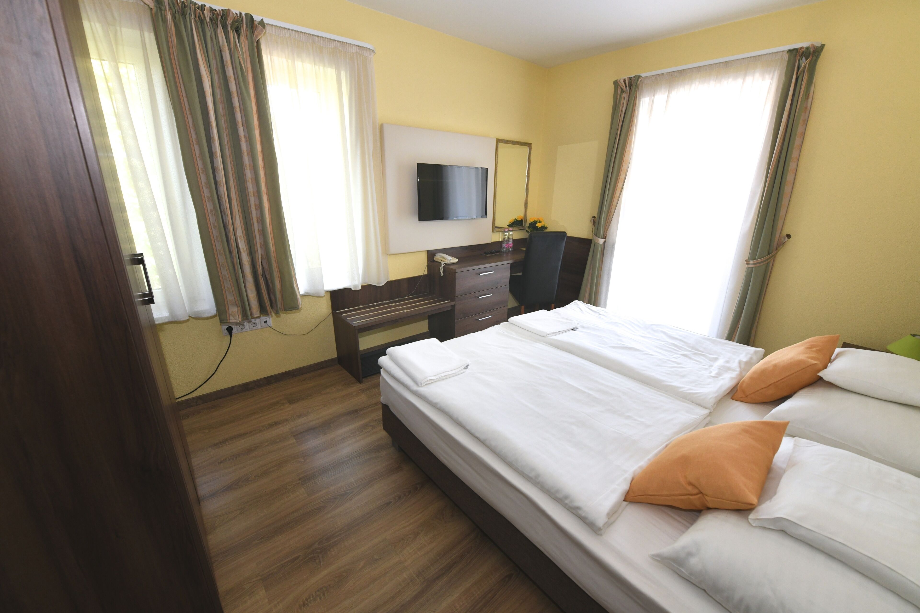 Een hotelkamer met een bed, een bureau, een stoel, een televisie en een raam met gordijnen.