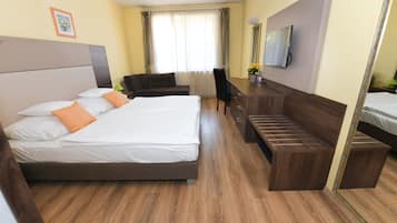 Habitación de hotel con dos camas, un escritorio, una silla y un televisor.