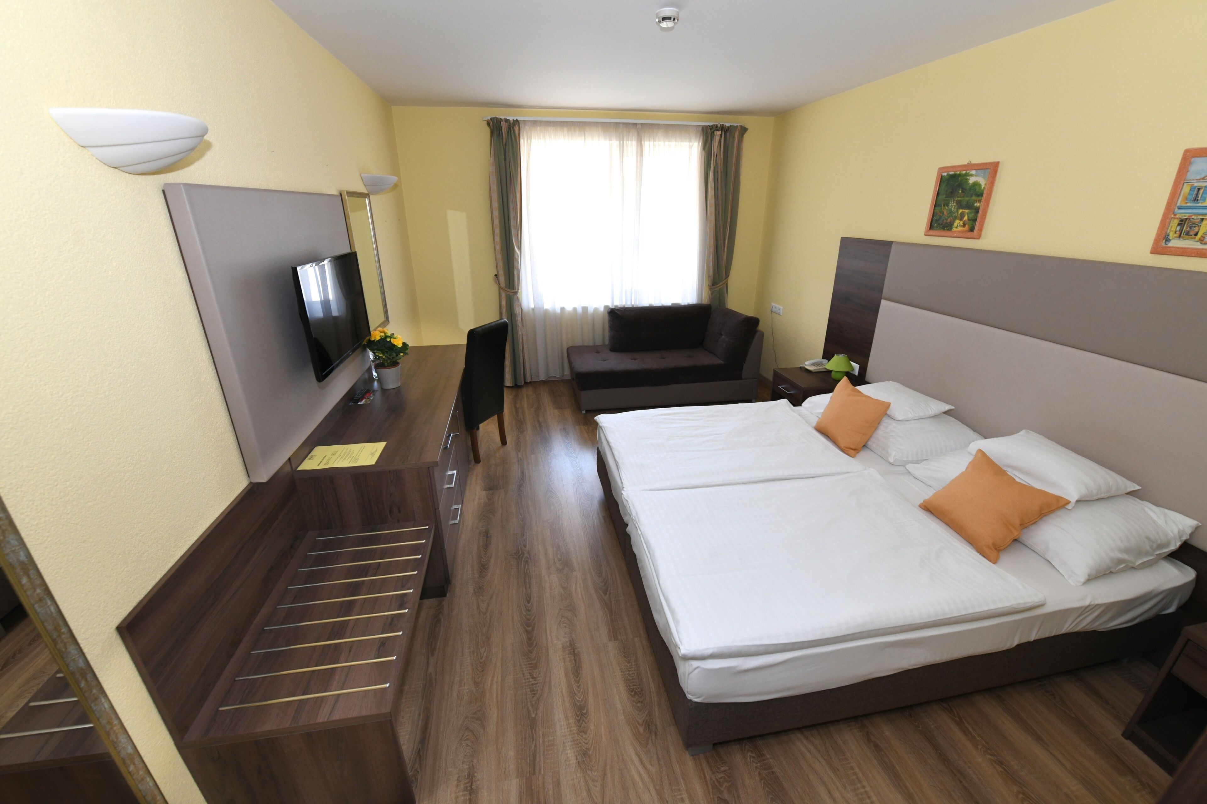 Habitación de hotel con una cama grande, televisión, escritorio y ventana con cortinas.