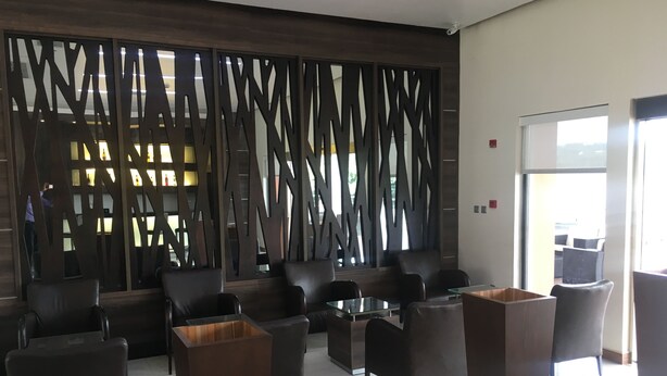 Un vestíbulo moderno con área de descanso, un muro decorativo y vistas al exterior.