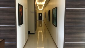 Un pasillo con obras de arte enmarcadas en las paredes, un cartel que indica una escalera y un techo moderno y bien iluminado.