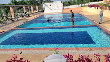 Una piscina al aire libre, sillones reclinables de piscina