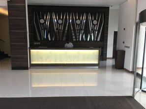 Una recepción de diseño moderno, con un separador de vidrio y un panel de madera con relojes.