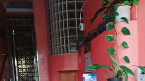 A reception desk with a potted plant, a blue brochure, and a poster on the wall. - Pension Albor (Gijon)