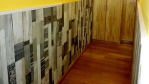 A hallway with a yellow wall, a patterned wall section, and wooden flooring. - Pension Albor (Gijon)