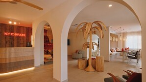 A spacious hotel lobby with a reception area, a dining area, and a seating space. - Sunset Oasis Ibiza- Adults Only (Sant Josep de sa Talaia)