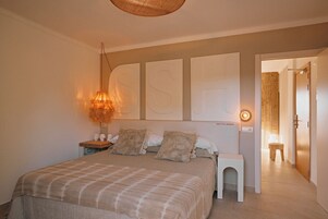 A bedroom with a bed, bedside tables, a lamp, and a wall with large letters.