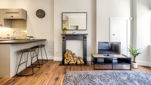 A modern kitchen with a bar area, a fireplace, a TV, and a potted plant. - Stylish Modern Apartment Parking (Edinburgh)