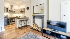 A modern kitchen with a central island, a fireplace, and a flat-screen TV. - Stylish Modern Apartment Parking (Edinburgh)