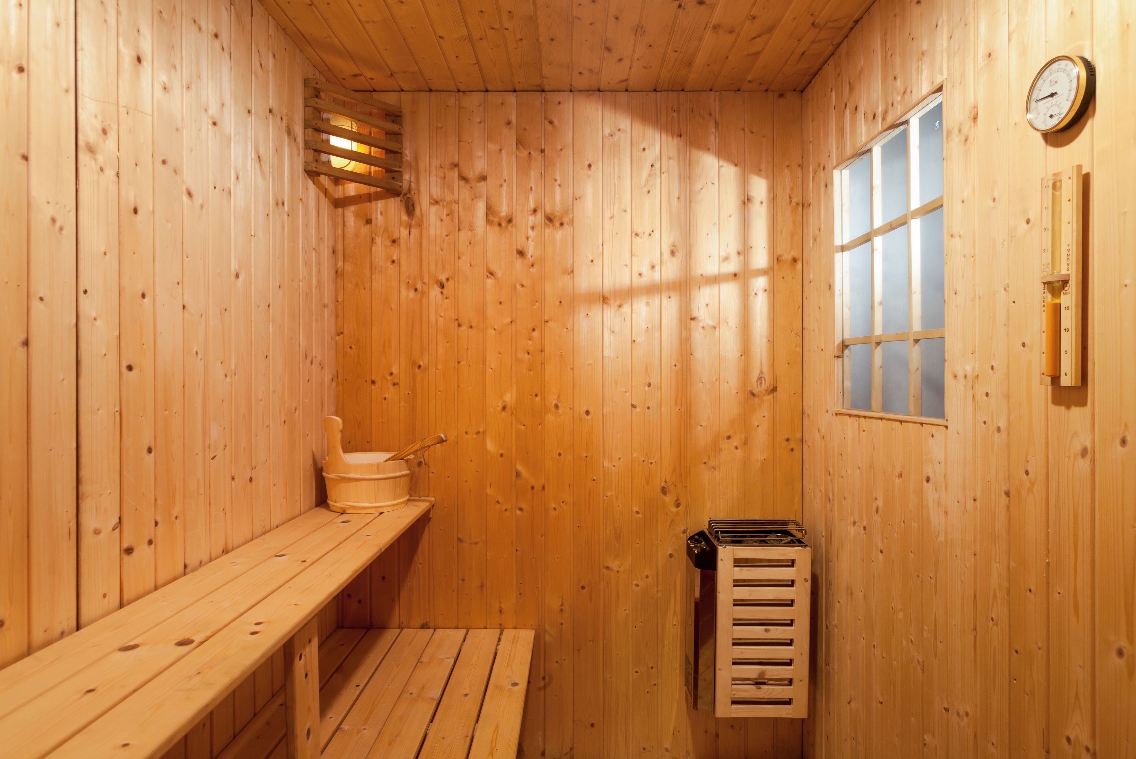 Una sauna de madera con un banco, una ventana y un termómetro en la pared.