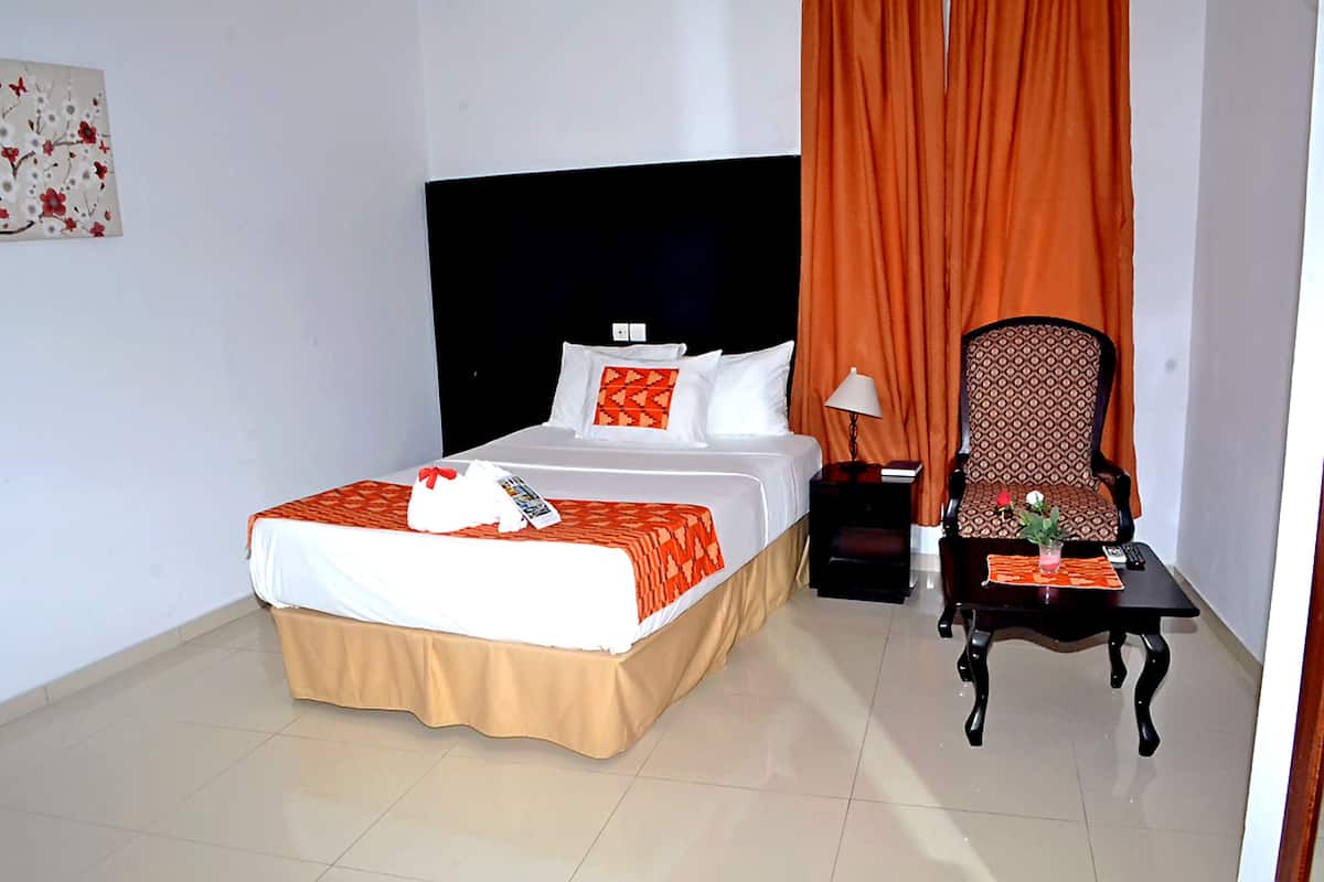 Una habitación de hotel con una cama, una silla, una mesa y una mesita de noche.