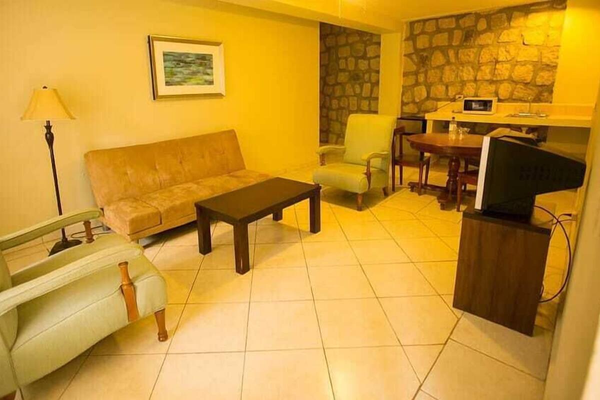 A living room with a sofa, armchair, coffee table, and a television on a stand.