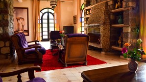 A cozy living room with a fireplace, stone walls, and a red carpet. - Tizi N'Ouirgane (Ouirgane)