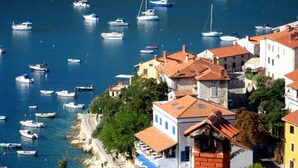 Un pueblo costero con barcos amarrados en el puerto y edificios con techos de tejas rojas.