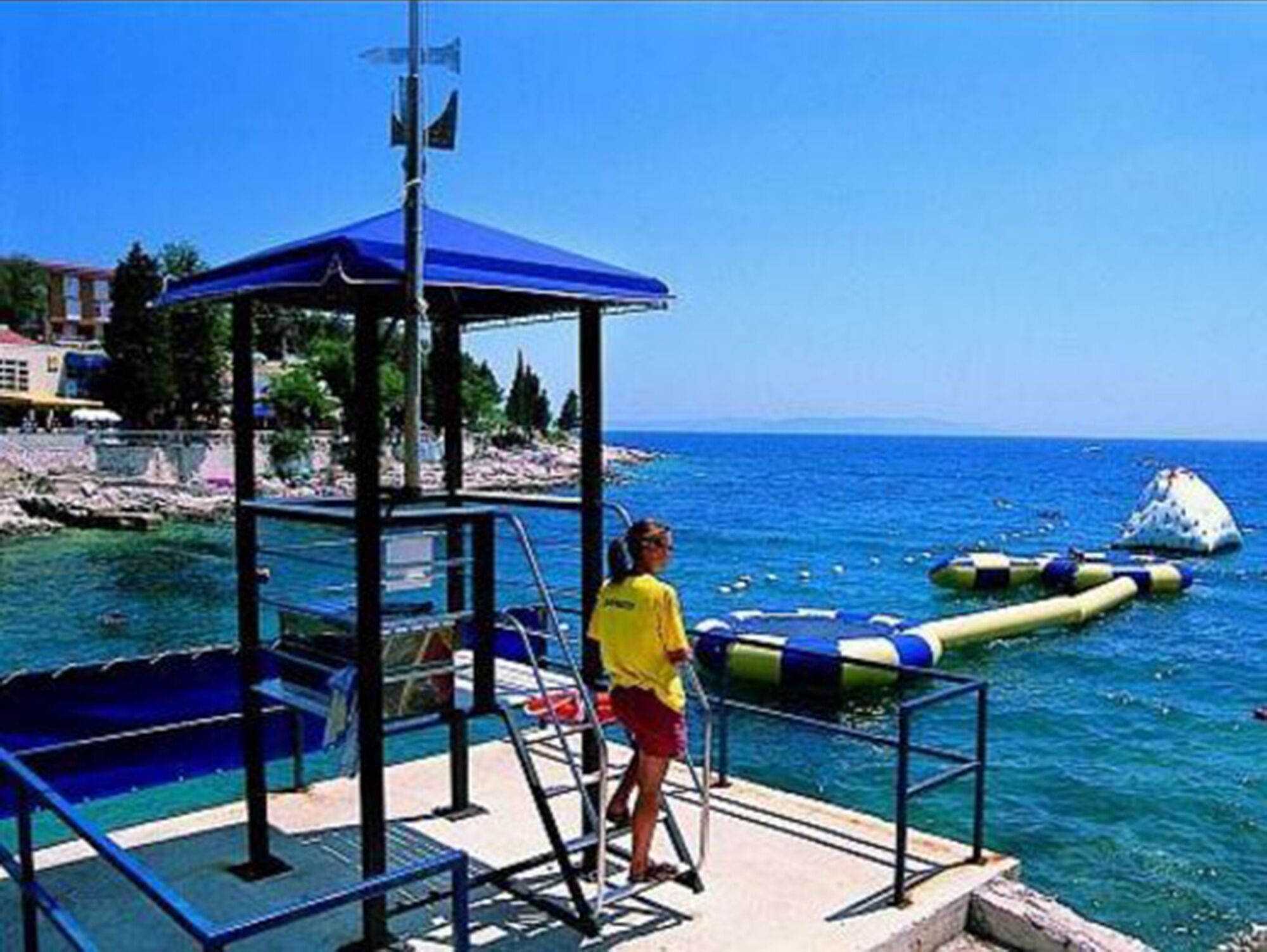 A pier with a blue canopy, a lifeguard stand, and a clear view of the sea.