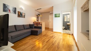 Una sala de estar moderna con un sofá seccional gris, piso de madera y obras de arte en las paredes.