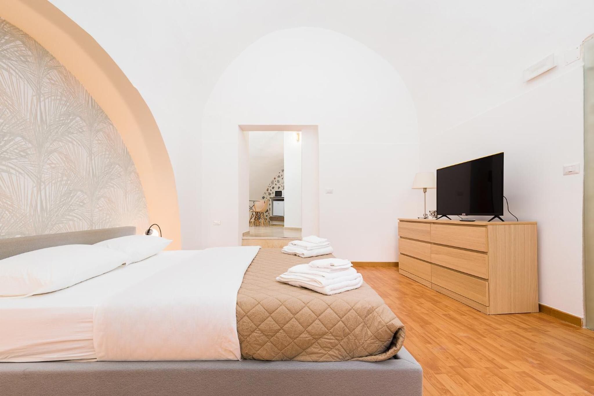 Un dormitorio con cama, televisión, cómoda y espejo.