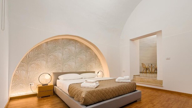 Un dormitorio moderno con cama, mesita de noche y vistas a un comedor.