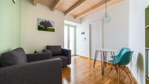 Un salón moderno con un sofá gris, sillas color turquesa y techo de madera.