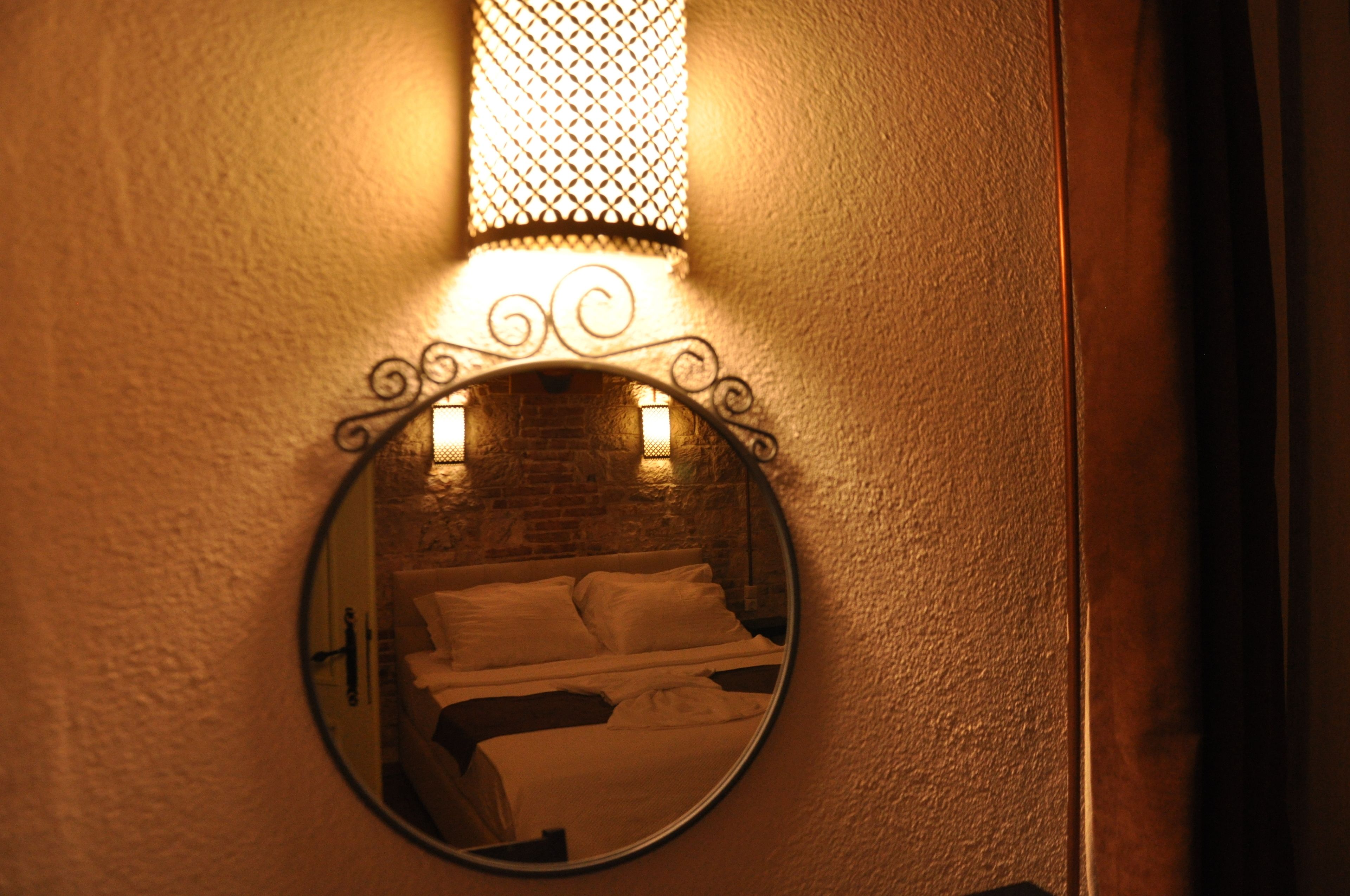 A round mirror with a brick wall and a bed in the reflection.