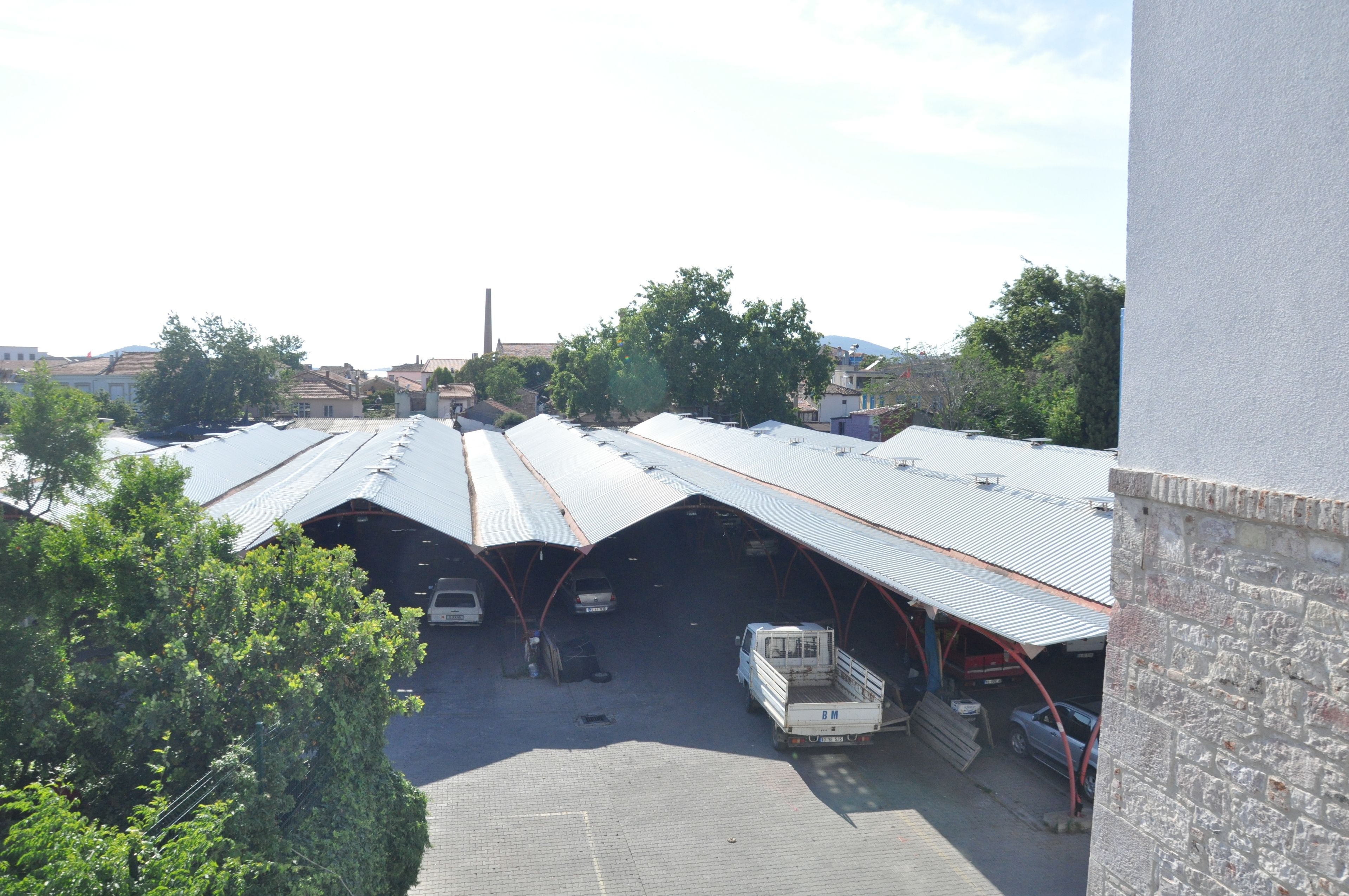 A parking area with multiple covered parking bays and a few vehicles.