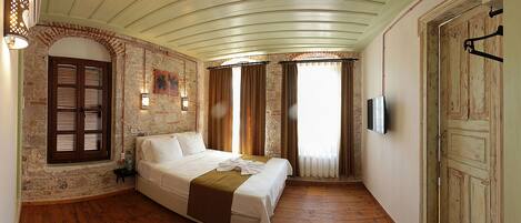 Un dormitorio con cama, pared de ladrillo, suelo de madera y puerta.