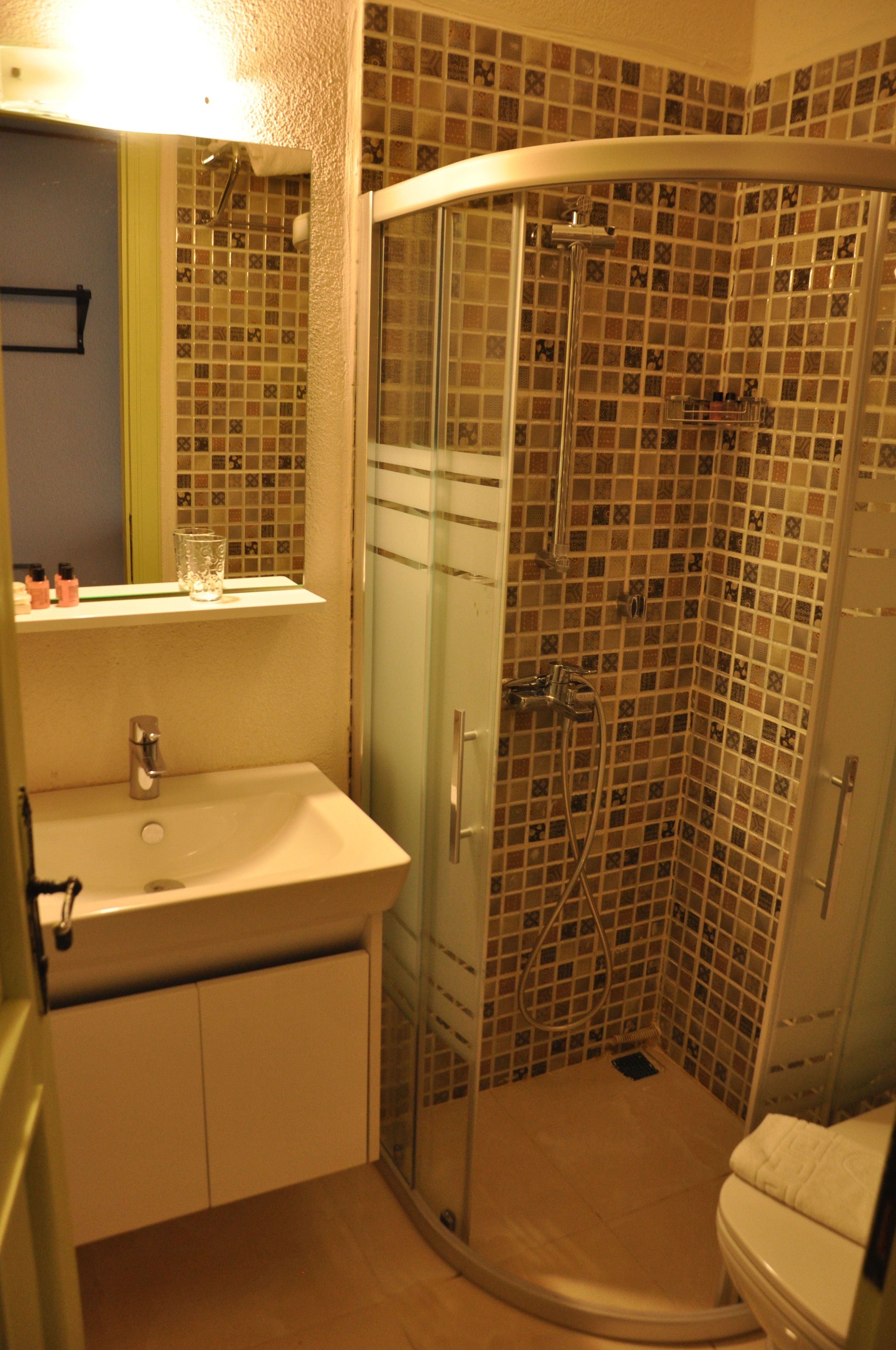 Un baño con ducha de vidrio, lavamanos y retrete.