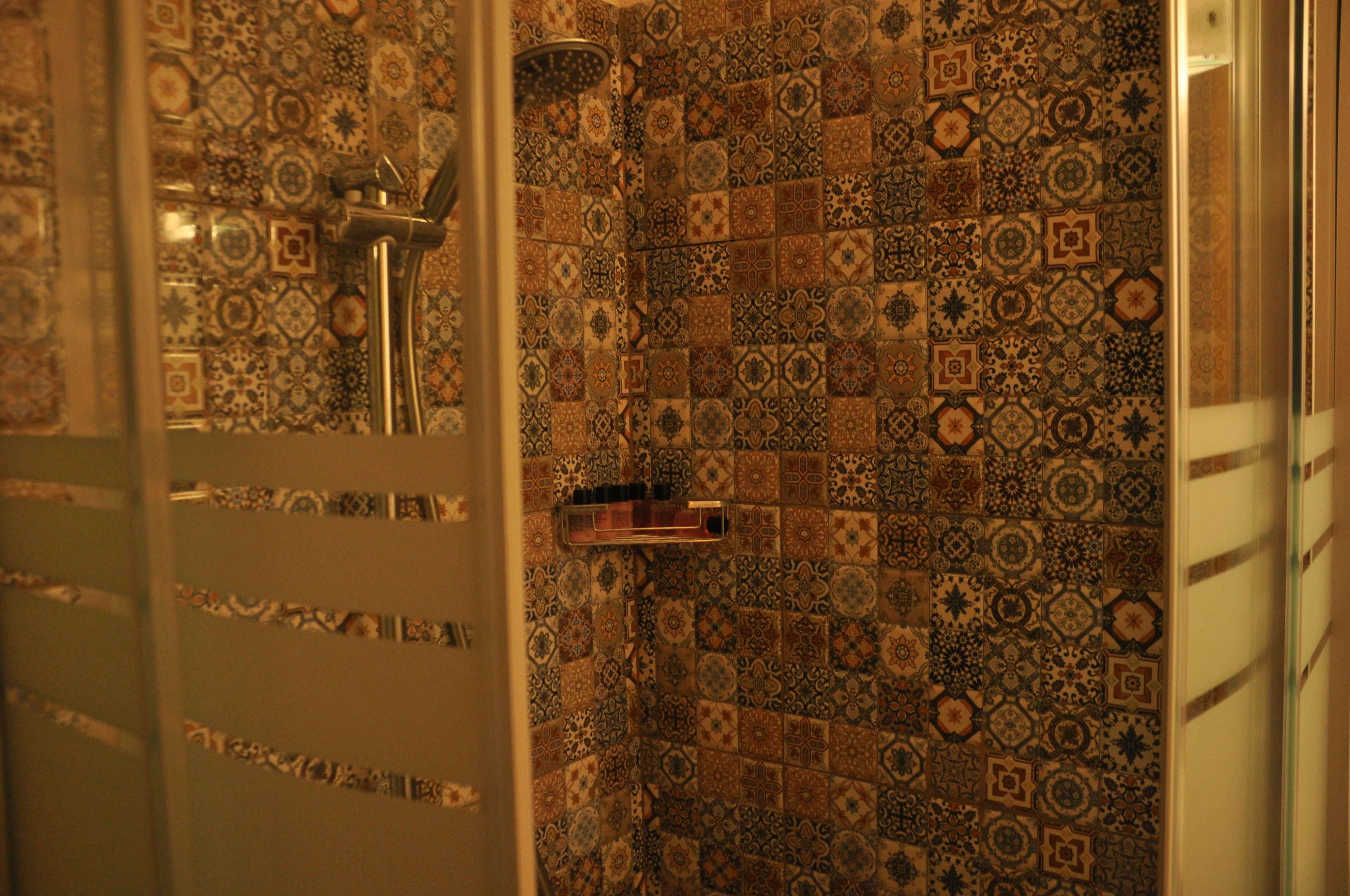 Un baño con azulejos estampados y una zona de ducha.