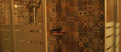 A bathroom with patterned tiles and a shower area.