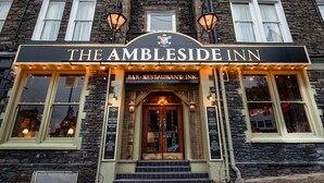 The exterior of The Ambleside Inn, featuring a stone facade, large windows, and a prominent entrance with a signboard. - The Ambleside Inn - The Inn Collection Group (Ambleside)