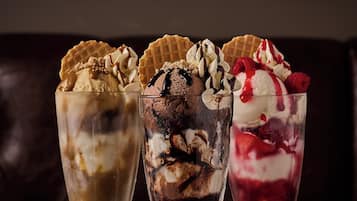 Three dessert glasses on a wooden table with a framed picture in the background.