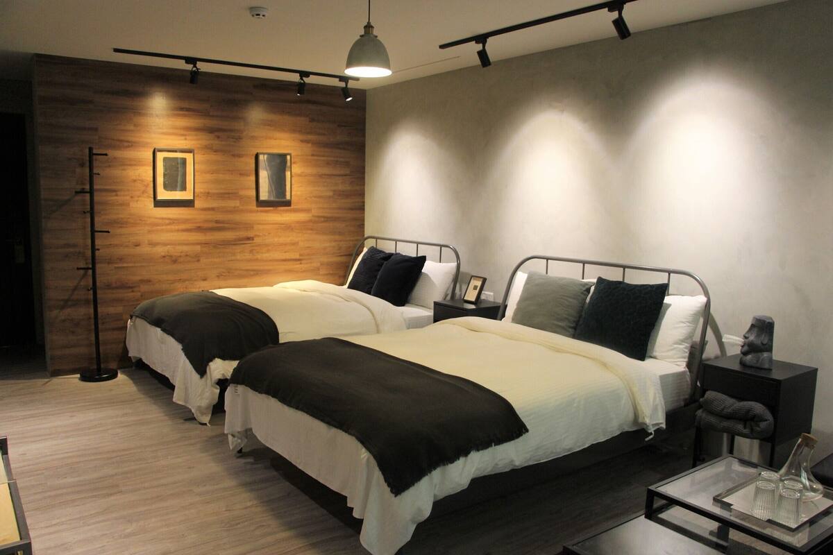 Habitación de hotel con dos camas, paneles de madera en una pared y un diseño moderno.