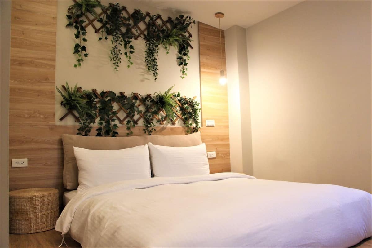 Un dormitorio con cama, cabecero de madera y un arreglo de plantas en la pared.