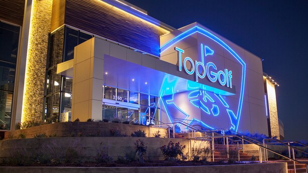A modern building with a neon sign reading "TopGolf" and a visible entrance with steps. - Holiday Inn Express & Suites Plano - The Colony by IHG (The Colony)