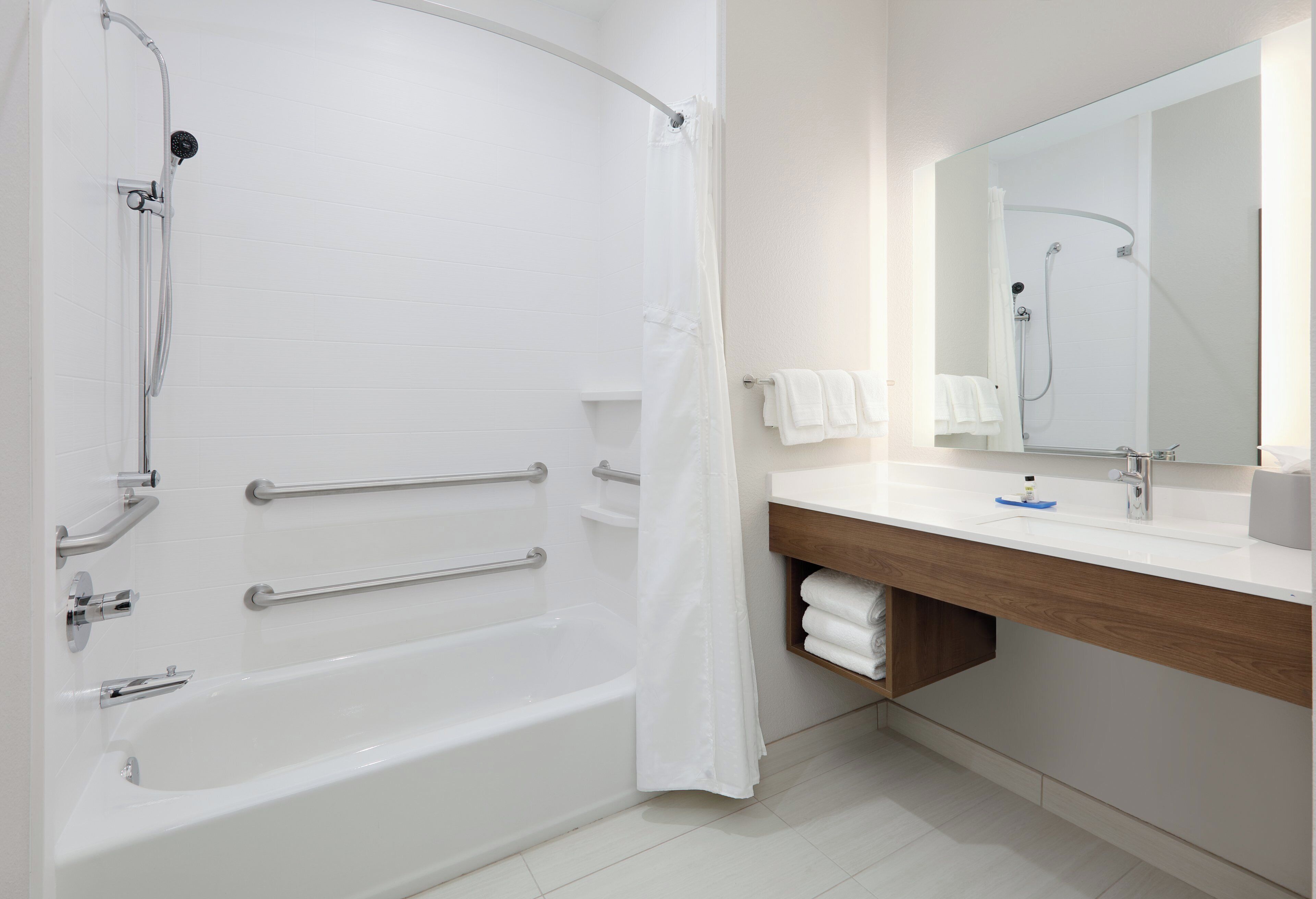 A modern bathroom with a bathtub, shower, and vanity.