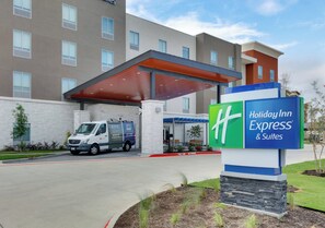 Een Holiday Inn Express & Suites met een overdekte ingang, een parkeerplaats en een gebouw met meerdere ramen.