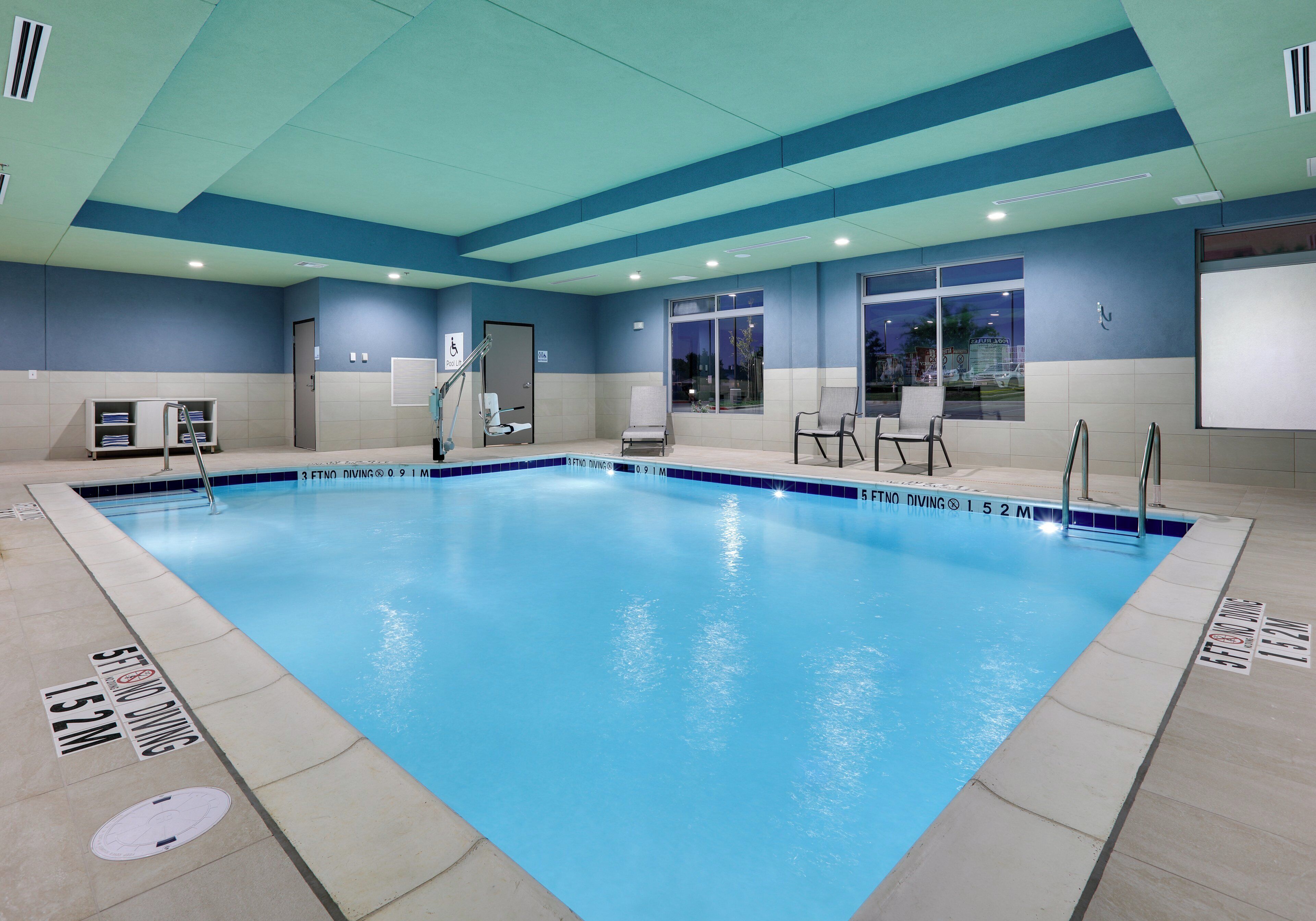 Una gran piscina interior con marcas de carriles bien definidas y una silla de socorrista.
