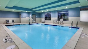 A large indoor swimming pool with clear lane markings and a lifeguard chair.