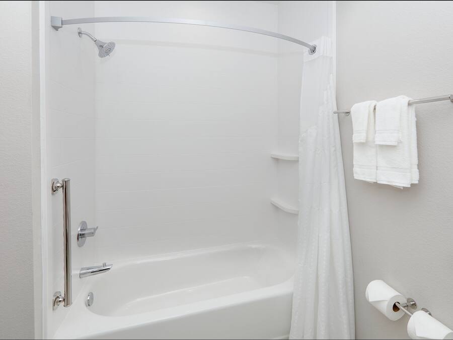 Un baño moderno con ducha a ras de suelo, bañera, toallero y dispensador de papel higiénico.